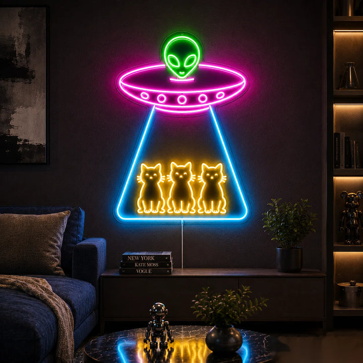 Colorful alien UFO LED neon sign with three glowing cats inside a spaceship beam, displayed as futuristic wall decor in a modern dark living room.