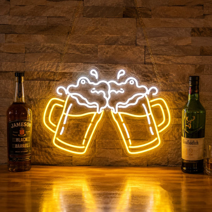 Warm yellow beer cheers neon sign with clinking beer mugs and foam detail displayed on a rustic stone wall in a stylish home bar setting.
