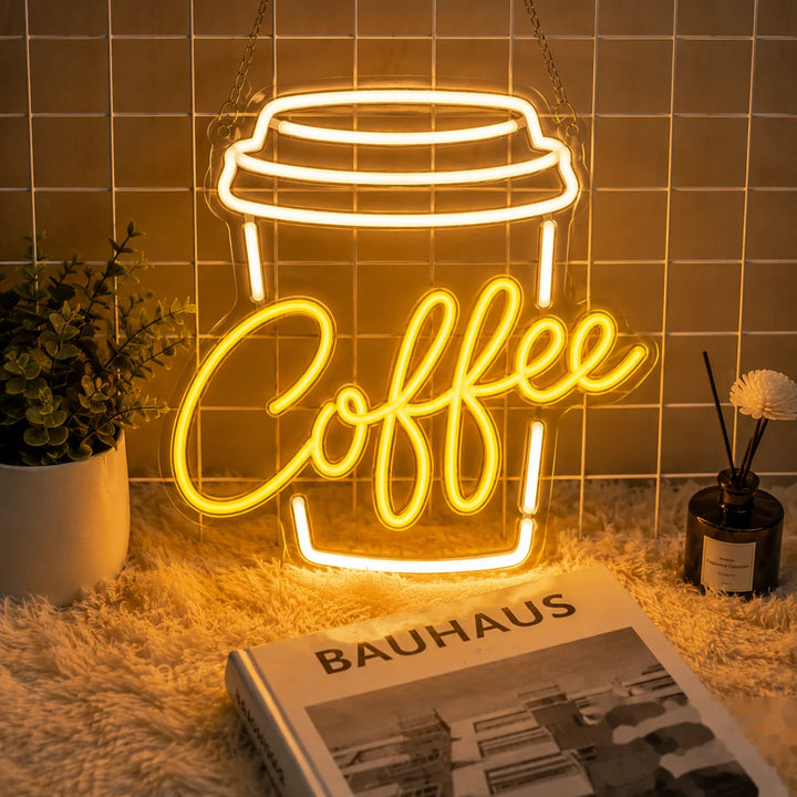 Warm yellow coffee cup LED neon sign hanging on a tiled wall with cozy café-style home decor and soft ambient lighting.