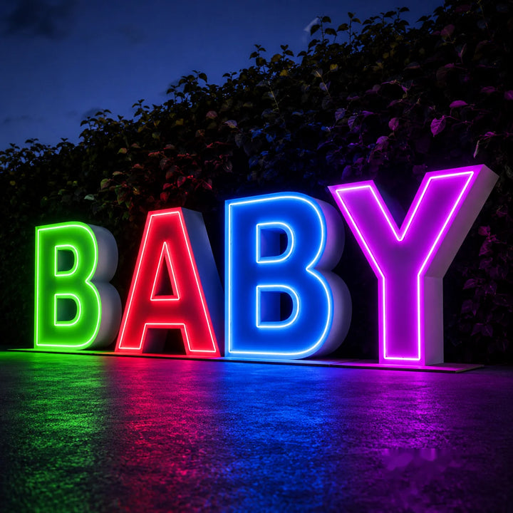 Colorful RGB BABY light-up letter sign with glowing neon-style illumination displayed outdoors at night for baby shower, gender reveal, or kids party decoration.