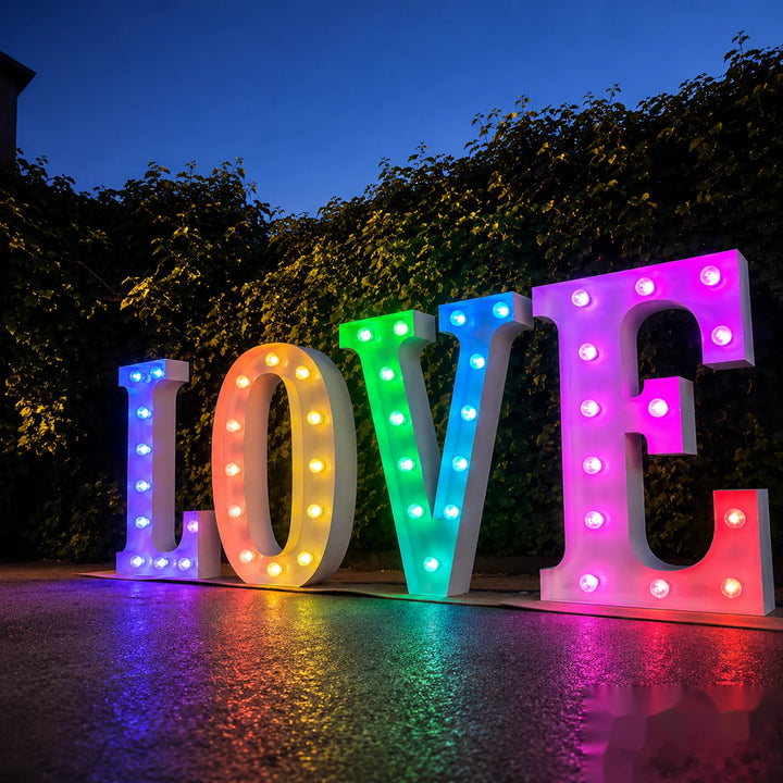 Large colorful LOVE marquee letters illuminated with LED bulbs in an outdoor evening setting, creating a vibrant backdrop for weddings, proposals, engagement parties, romantic events, and photo opportunities.
