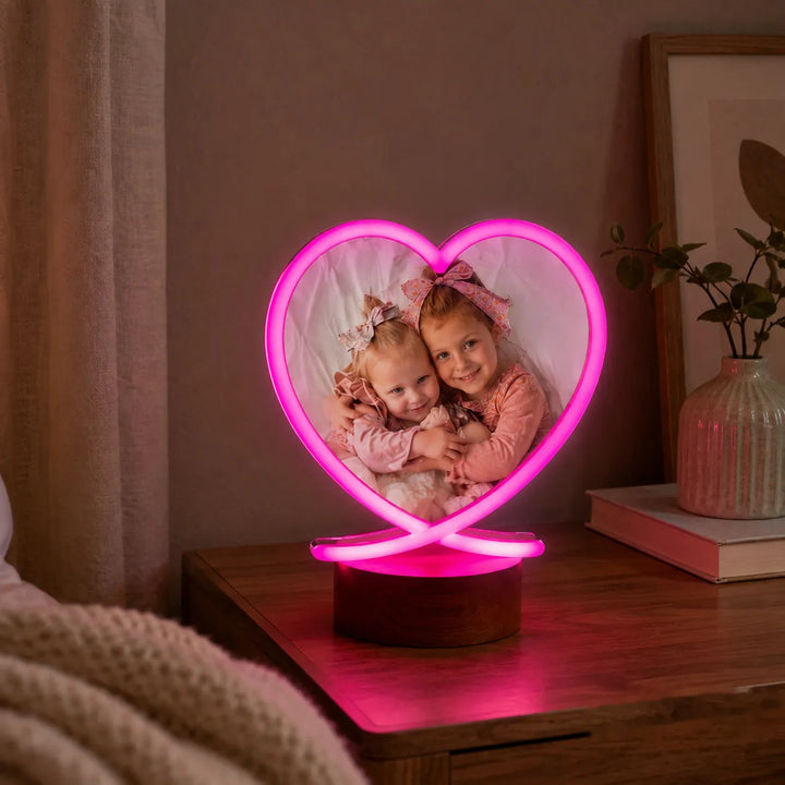Custom photo neon lamp with a pink heart-shaped LED neon light framing a personalized picture of two sisters, designed as a unique family keepsake and room decor.