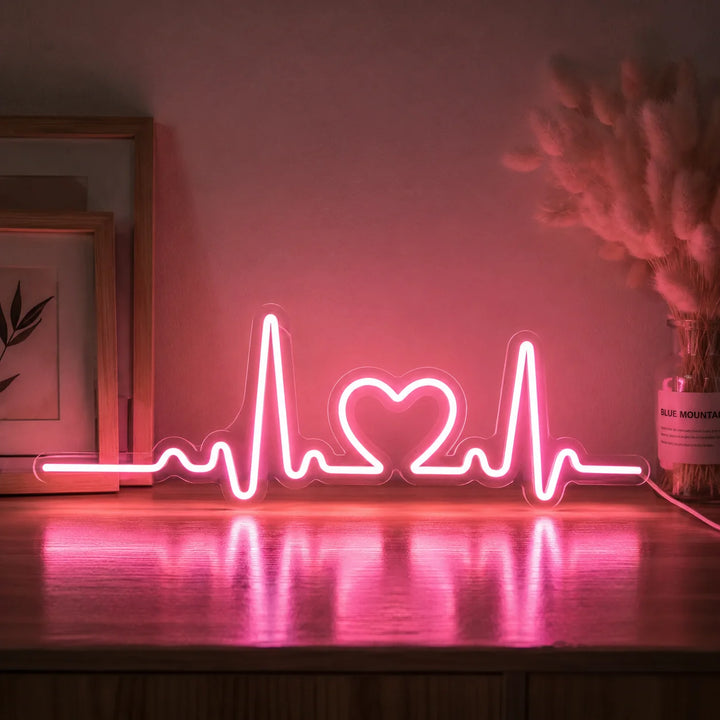 Minimal pink heart pulse neon light sign glowing on a wooden surface with warm reflections, ideal for romantic bedroom decor and aesthetic home lighting.