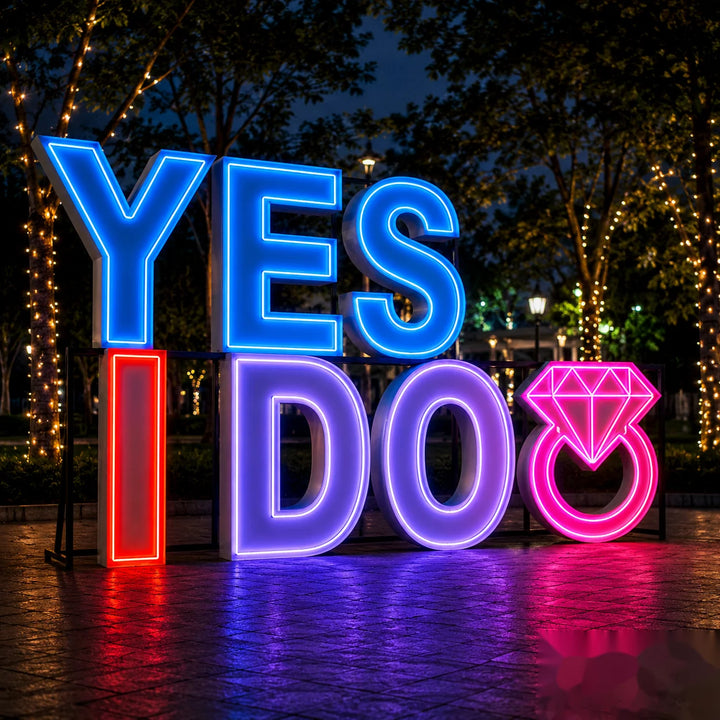 Bright LED illuminated “YES I DO” proposal sign with engagement ring icon, displayed outdoors at night with colorful lighting, perfect for marriage proposals, engagement parties, wedding décor, and romantic event photography.